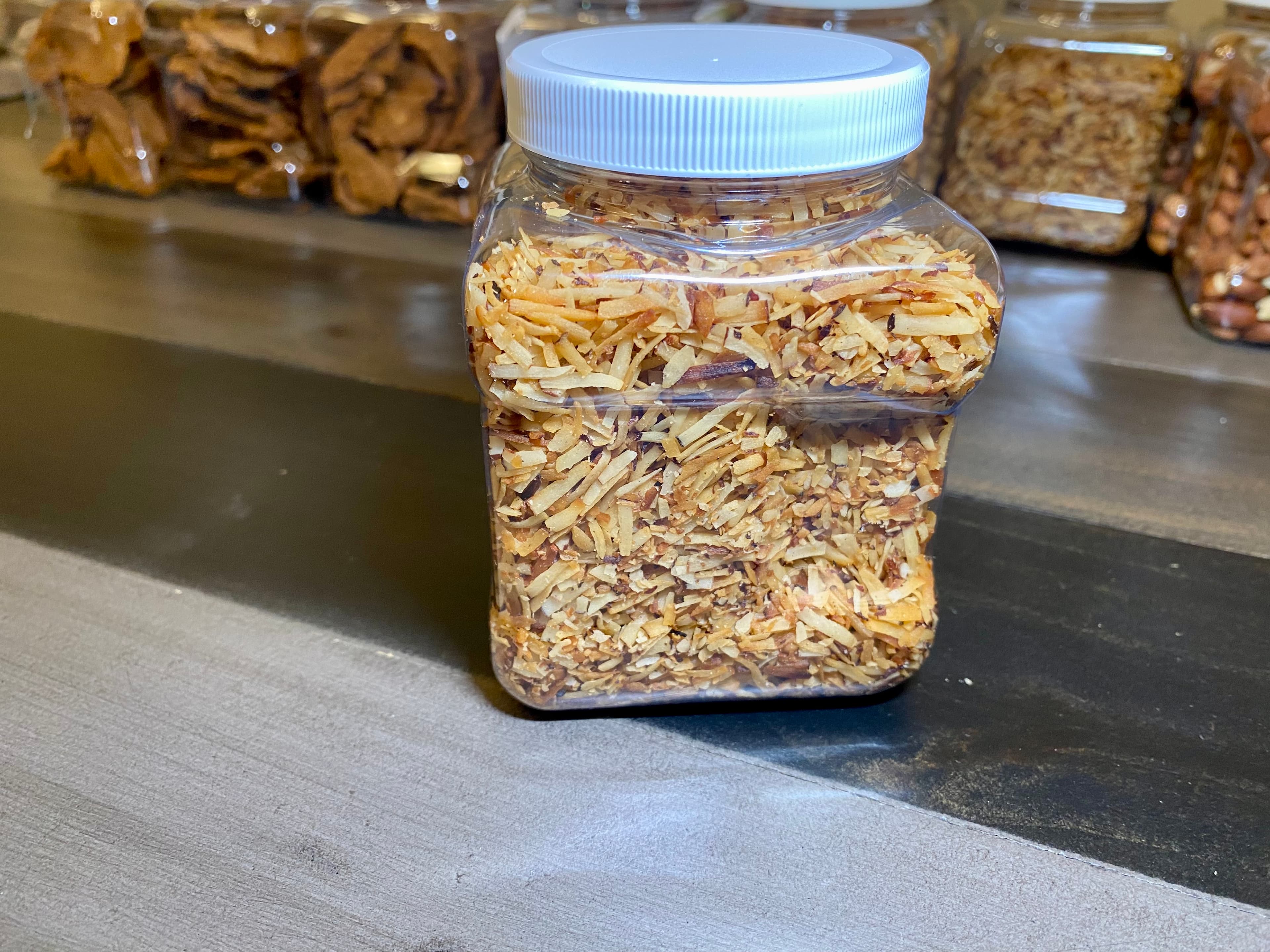 A clear jar filled with toasted coconut strips